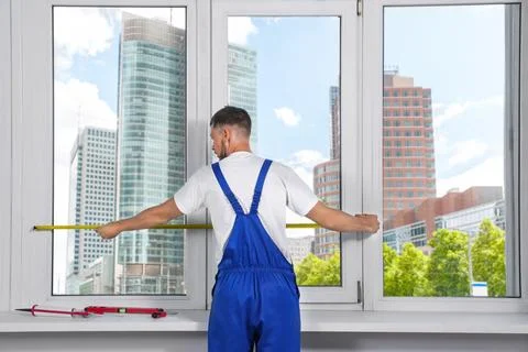 Worker measuring plastic window indoors, back view. Installation process Stock Photos