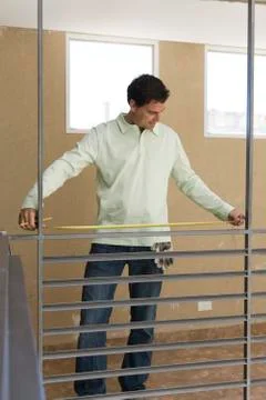 Worker measuring railing between two support columns Stock Photos