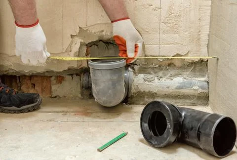 A worker is measuring the sewage drain pipe. Stock Photos