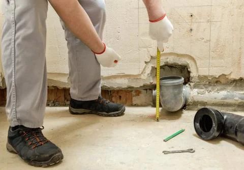 A worker is measuring the sewage drain pipe. Stock Photos