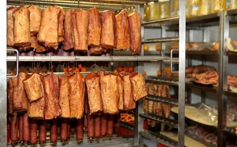 A worker at the meat processing factory, prepares sausages at the work table Stock Photos