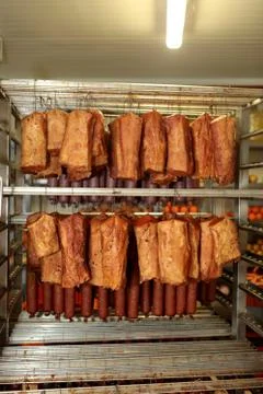 A worker at the meat processing factory, prepares sausages at the work table Stock Photos