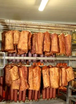 A worker at the meat processing factory, prepares sausages at the work table Stock Photos