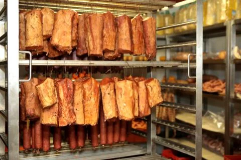 A worker at the meat processing factory, prepares sausages at the work table Stock Photos