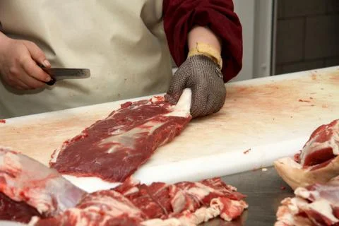 A worker at the meat processing factory, prepares sausages at the work table Stock Photos