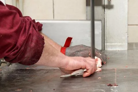 A worker at the meat processing factory, prepares sausages at the work table Stock Photos