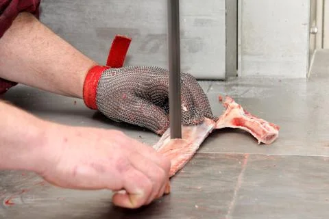 A worker at the meat processing factory, prepares sausages at the work table Stock Photos