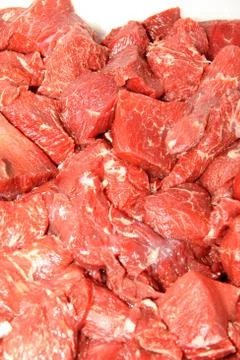 A worker at the meat processing factory, prepares sausages at the work table Stock Photos