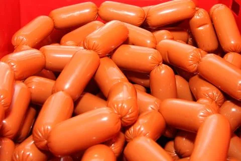 A worker at the meat processing factory, prepares sausages at the work table 스톡 사진