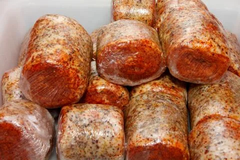 A worker at the meat processing factory, prepares sausages at the work table Stock Photos