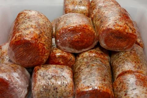A worker at the meat processing factory, prepares sausages at the work table Stock Photos