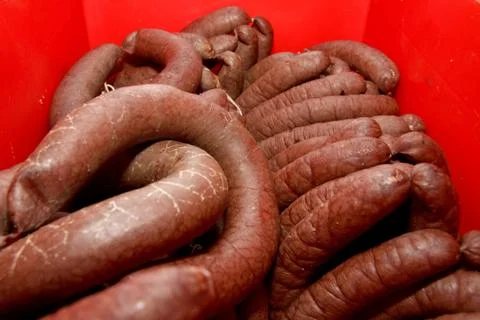 A worker at the meat processing factory, prepares sausages at the work table Stock Photos