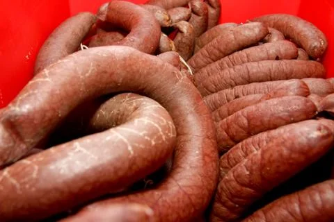 A worker at the meat processing factory, prepares sausages at the work table Stock Photos