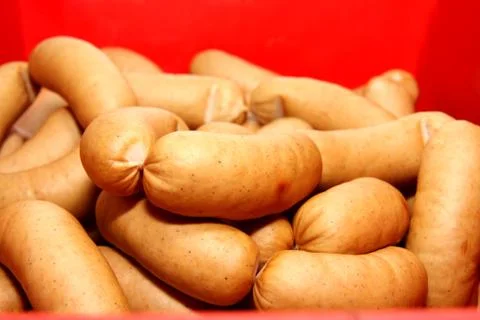 A worker at the meat processing factory, prepares sausages at the work table Stock Photos
