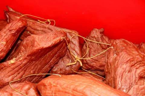 A worker at the meat processing factory, prepares sausages at the work table Stock Photos