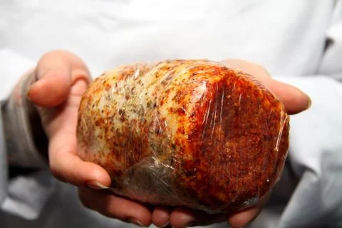 A worker at the meat processing factory, prepares sausages at the work table Foto stock