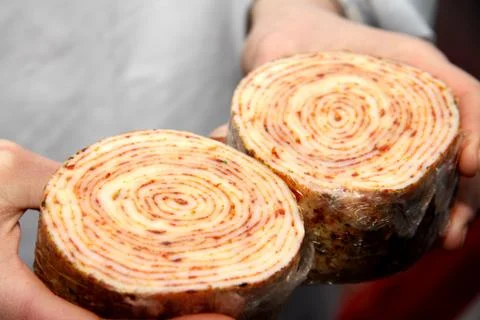 A worker at the meat processing factory, prepares sausages at the work table Stock Photos