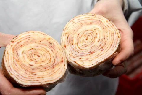 A worker at the meat processing factory, prepares sausages at the work table Stock Photos