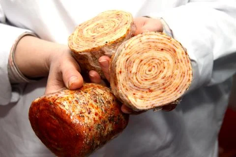 A worker at the meat processing factory, prepares sausages at the work table Stock Photos