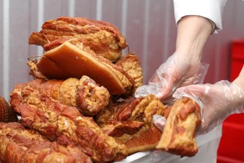 A worker at the meat processing factory, prepares sausages at the work table Stock Photos