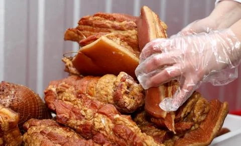 A worker at the meat processing factory, prepares sausages at the work table Stock Photos