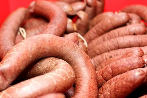 A worker at the meat processing factory, prepares sausages at the work table Stock Photos