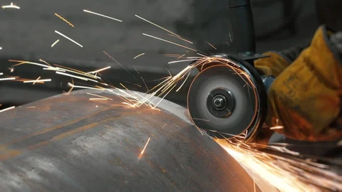 A worker at a metalworking plant processes a large pipe with a grinder. Stock Footage 306541733