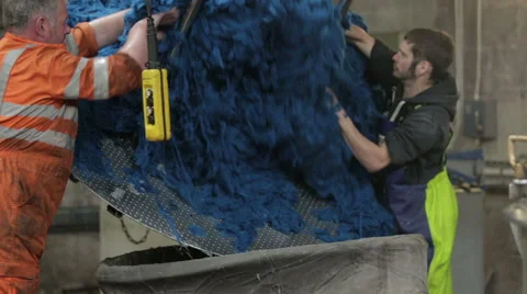 Worker in a mill removing dye'd wool from a large container Stock Footage 58496267