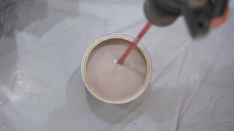 Worker mixes brown paint with special drill nozzle in bucket Stock Footage 124608097