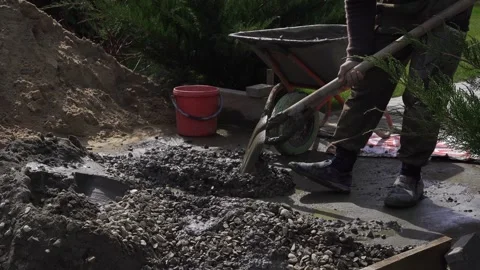 A worker mixes the concrete mixture with a hand shovel Stock Footage 307384839