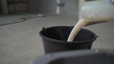 A worker mixes the mixture with a measuring vessel. The worker mixes the liqu Stock Photos
