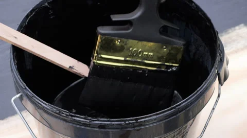 Worker mixing black bitumen paint in a bucket Stock Footage 338348558