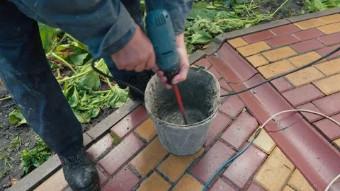Worker is mixing concrete in special pot with long drill on street Stock Footage 166175212