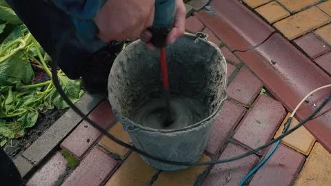 Worker is mixing concrete in special pot with long drill on street Stock Footage 166175246