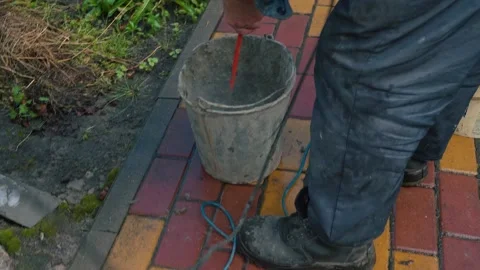 Worker is mixing concrete in special pot with long drill on street Stock Footage 166175314