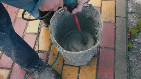 Worker is mixing concrete in special pot with long drill on street Stock Footage 166175339