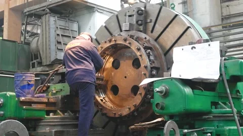 A worker monitors how a large metal part is processed on a machine in the Video stock 312737822