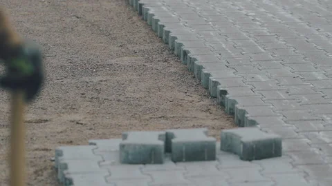 The worker monitors how the machine automatically installs the gray pavement Vidéo 195693443