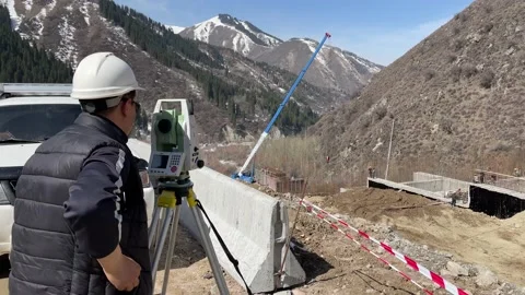A worker monitors the repair of the dam through geodetic equipment. Stock Footage 187500292