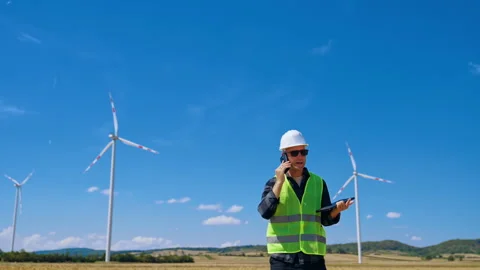 Worker monitors wind turbines while using phone and tablet in the field. A man Video stock 342737392