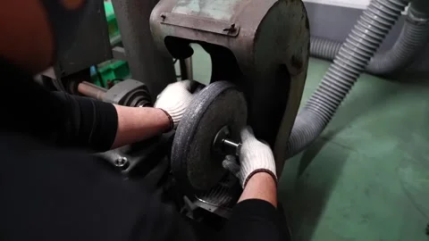 Worker mounting abrasive grinding wheel onto spindle machine with gloved hands Stock Footage 340156095