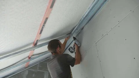 Worker mounting metal construction for drywall in a newly built house Stock Footage 81171815