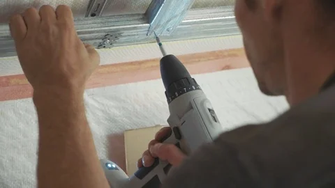 Worker mounting metal construction for drywall in a newly built house Stock Footage 81196709