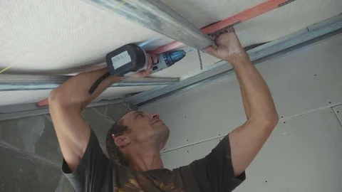 Worker mounting metal construction for drywall in a newly built house Stock Footage 81197503