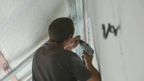 Worker mounting metal construction for drywall in a newly built house Stock Footage 81198343