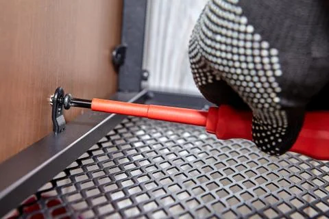 Worker is mounting metal flat pack furniture using screwdriver. Foto stock