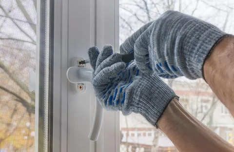 Worker mounts the handle to the window frame made of plastic. Creating comfor Stock Photos