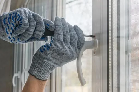 Worker mounts the handle to the window frame made of plastic. Creating comfor Stock Photos
