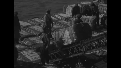 Worker moves cotton bales onto ship with the help of conveyor belt - 1930 Stock Footage 101714246