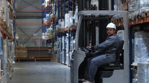 The worker moves on a lifting machine through a logistic warehouse. 4K Slow Mo Stock Footage 111764345